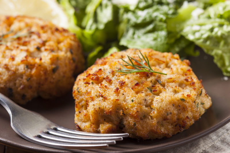 Crab cakes on a plate with a fork | Food For Net A black plate with crab cakes