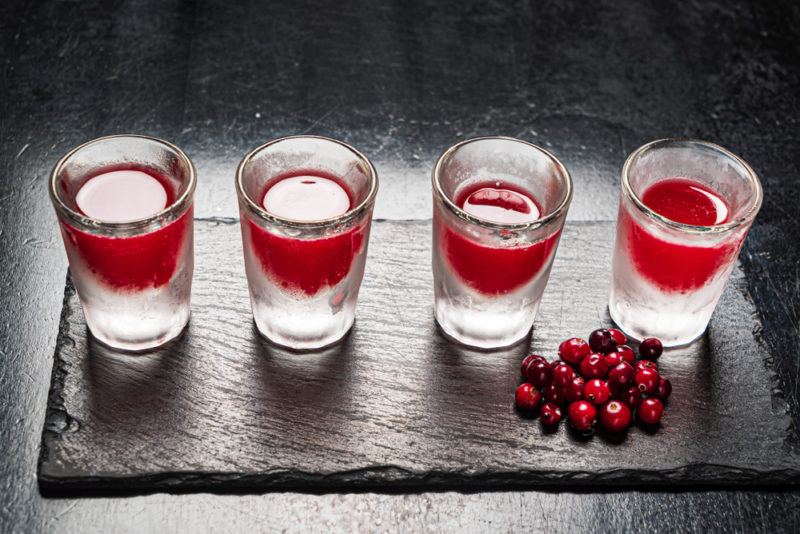 Four cranberry shots on black slate with cranberries