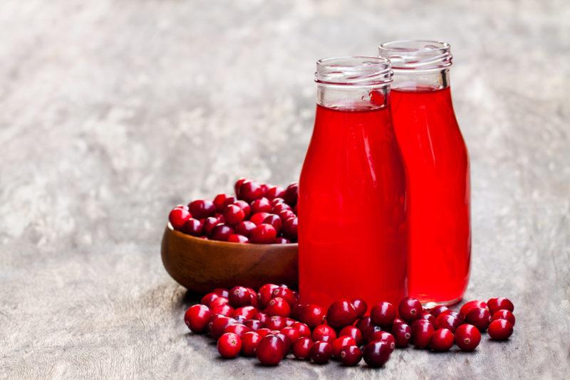 Two bottles of cranberry juice with cranberries