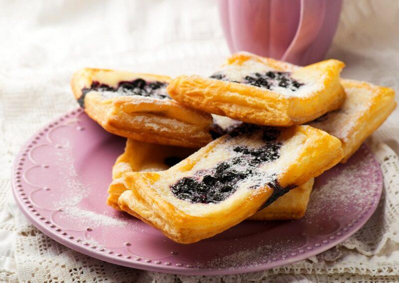 A pink plate with four or five cream cheese and berry danishes