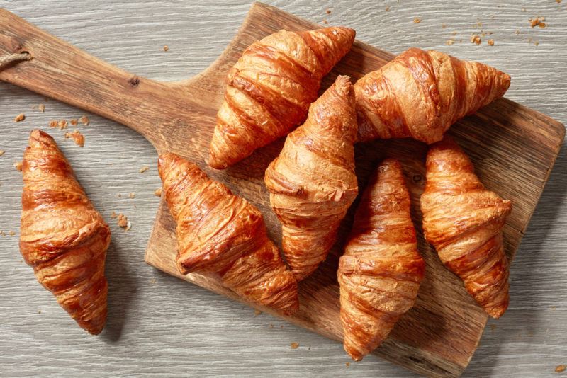 A wooden board containing various croissants