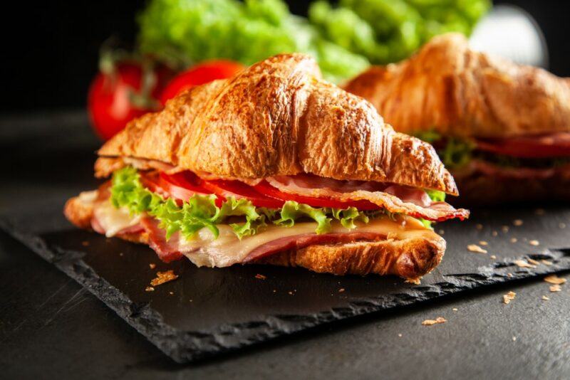 Two croissants that have been sliced open and contain turkey bacon, lettuce, and tomato