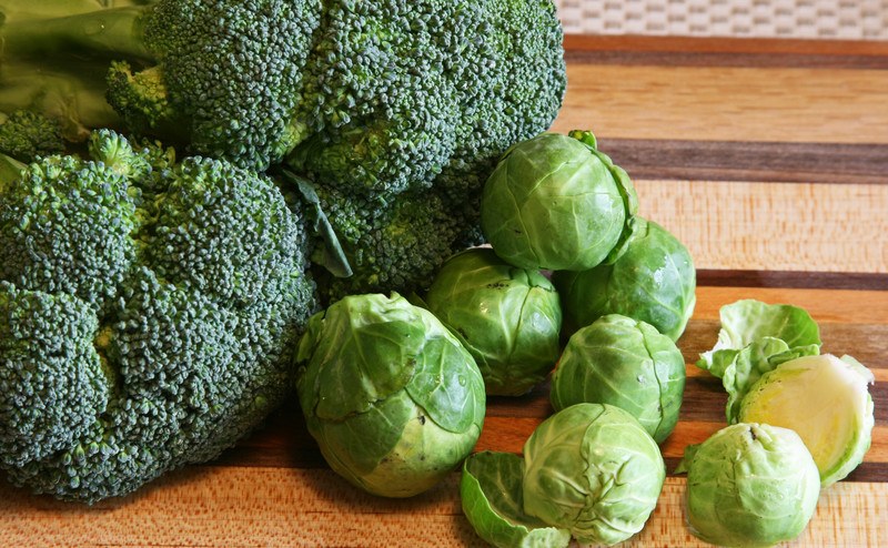 This photo shows raw broccoli and brussels sprouts on a cutting board.