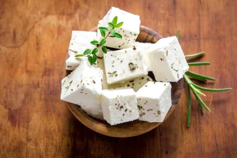 Cubes of feta cheese with rosemary in a bowl on a table