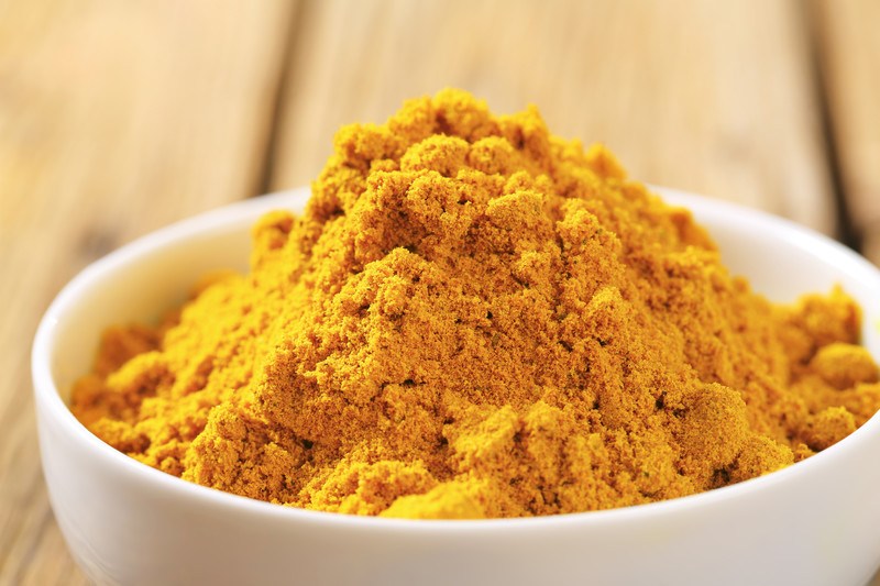 closeup image of white ceramic bowl full of curry powder 