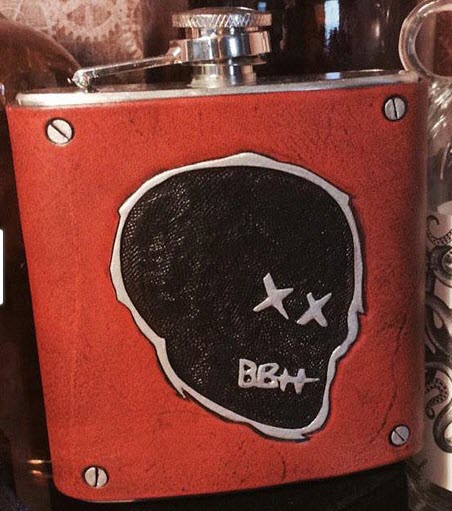 Custom-Handmade-Leather-Flasks | Food For Net A stainless steel flask with a red cover and black skull.