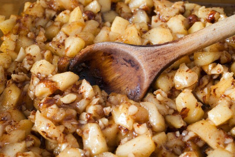 Apple chunks that have been baked with cinnamon and have a wooden spoon in them