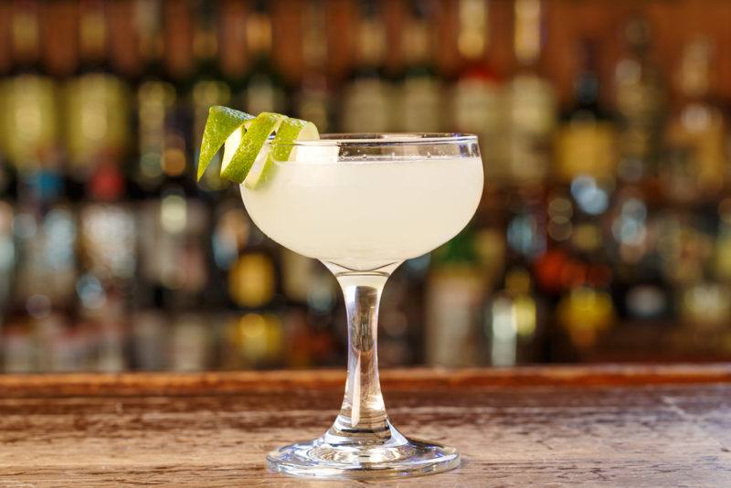 A light colored daiquiri cocktail in front of a bar