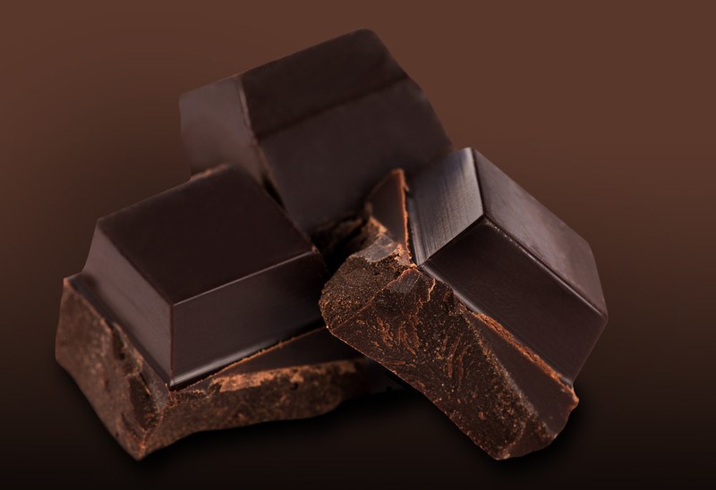 This photo shows three squares of dark chocolate against a brown background.