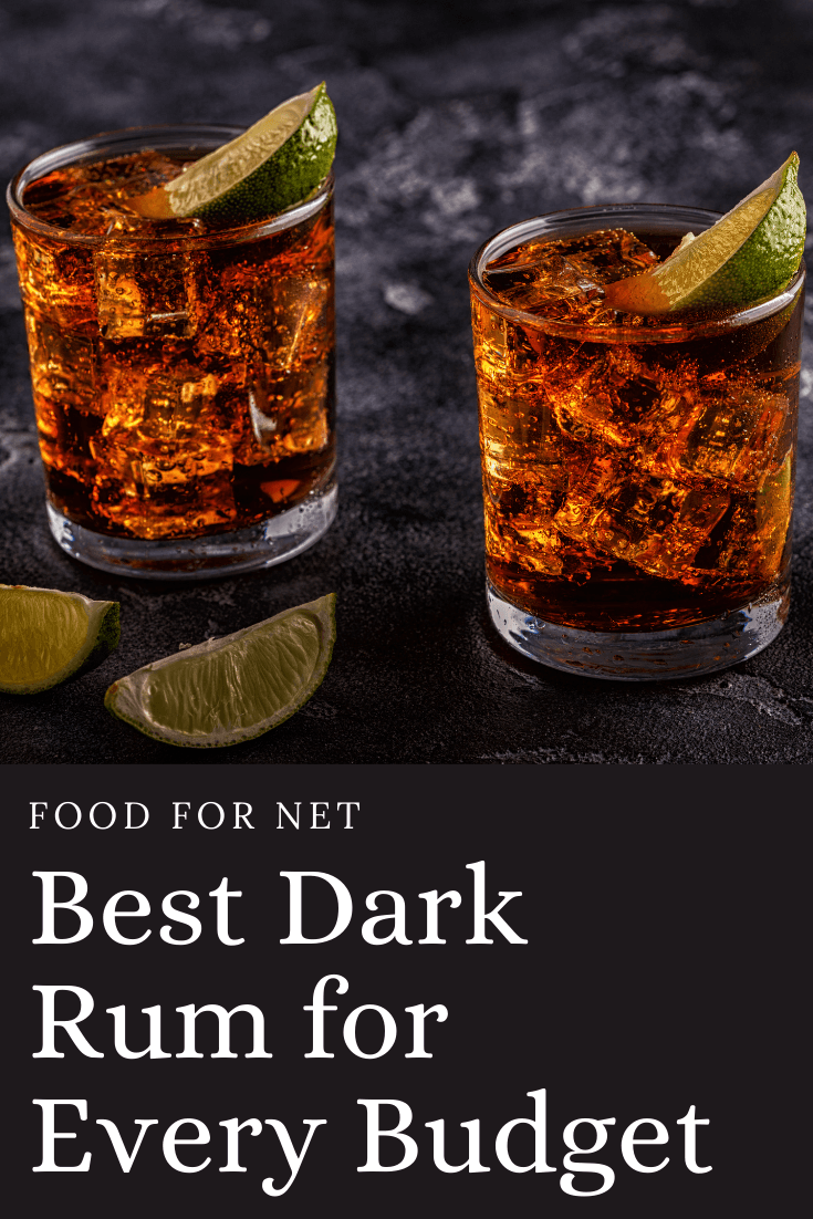 Two glasses of dark rum with lime on a dark table