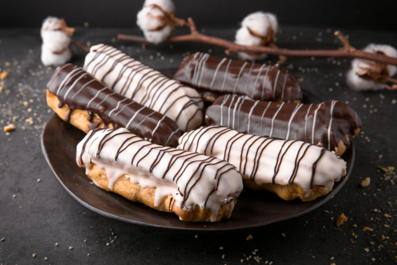 A black plate with milk chocolate and white chocolate eclairs