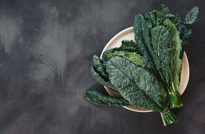 A plate on a chalk table with dark leafy greens