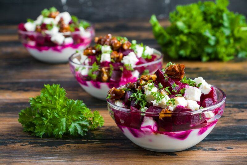 Three glass bowls containing a Greek yogurt, walnut, and beets