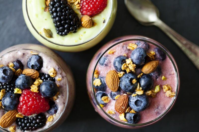 Three glasses of smoothies with berries and nuts on the top