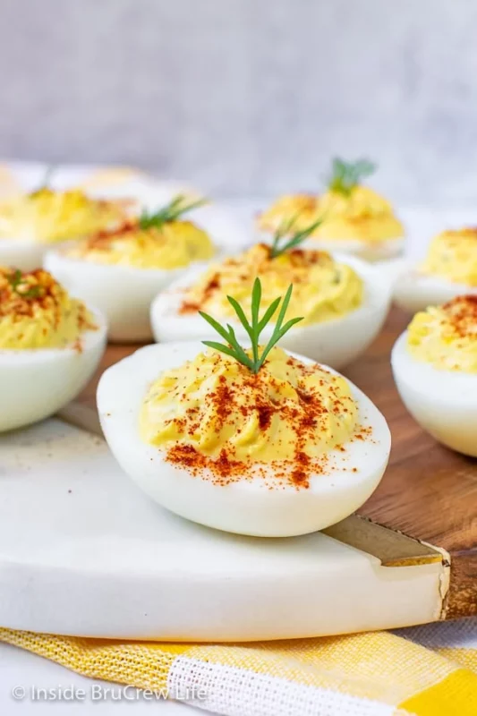 A wooden tray with a small number of dill pickled deviled eggs