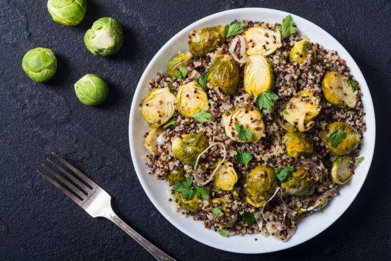 A white dish that contains a dinner made using quinoa and brussels sprouts