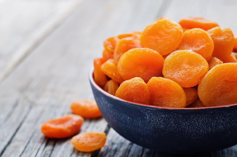 A black bowl containing dried apricots