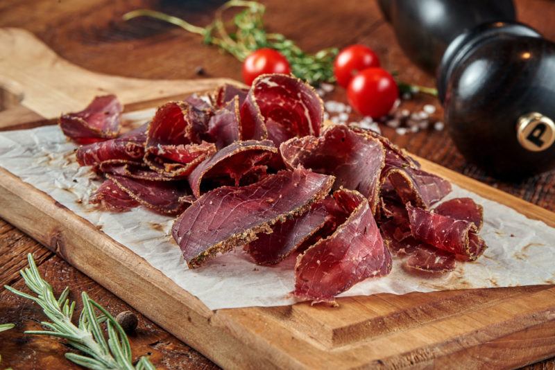 A wooden board with thinly sliced jerky