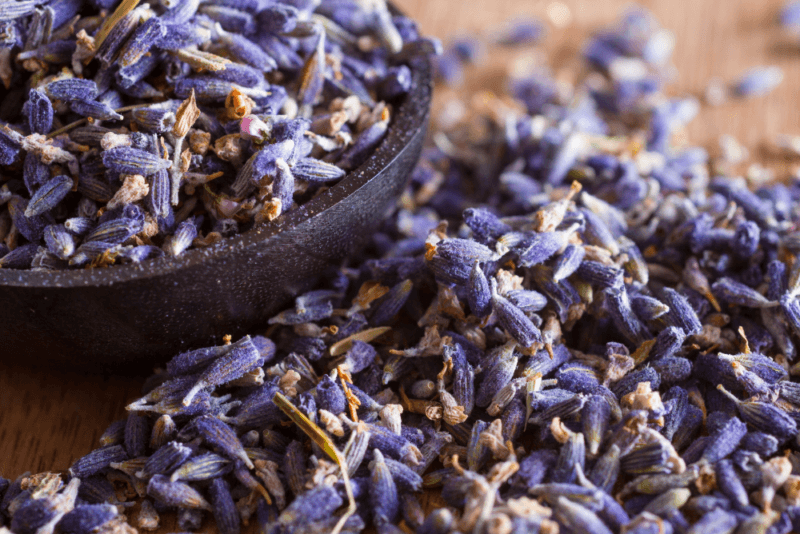 A collection of dried lavender buds on a table and in a black bowl