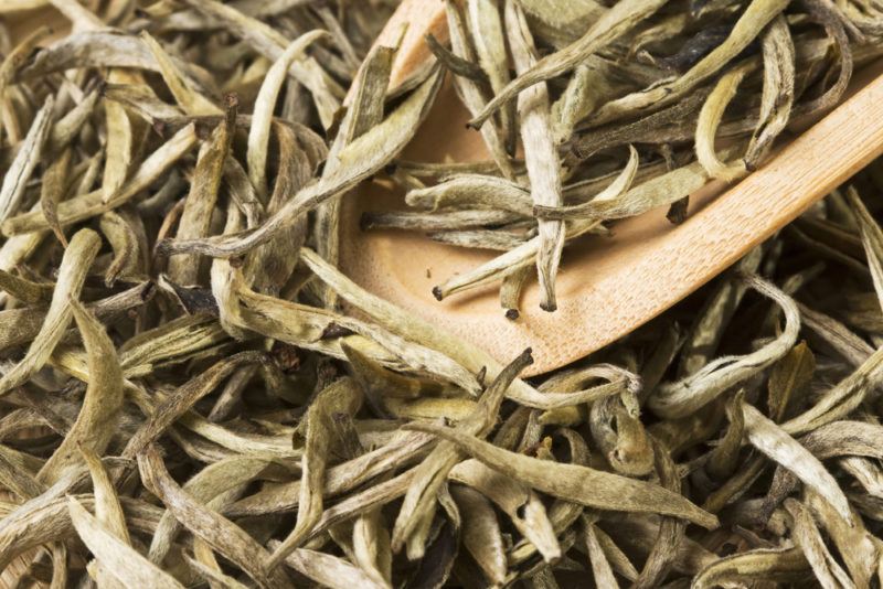 Dried white tea leaves with a wooden spoon