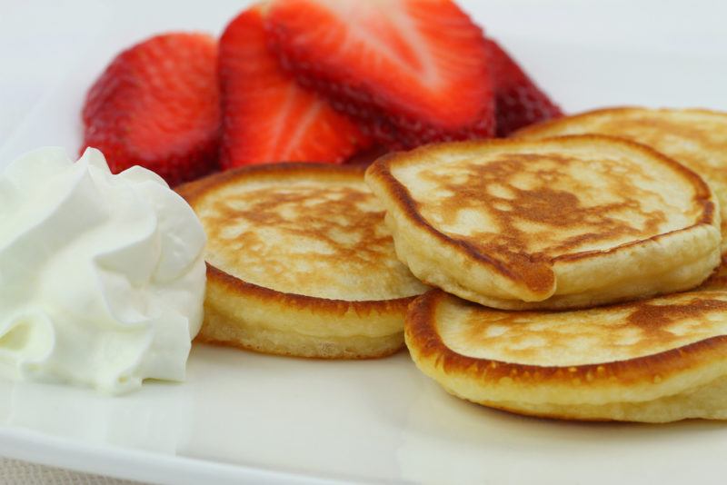 Drop scones, or pikelets, on a plate with strawberries and cream