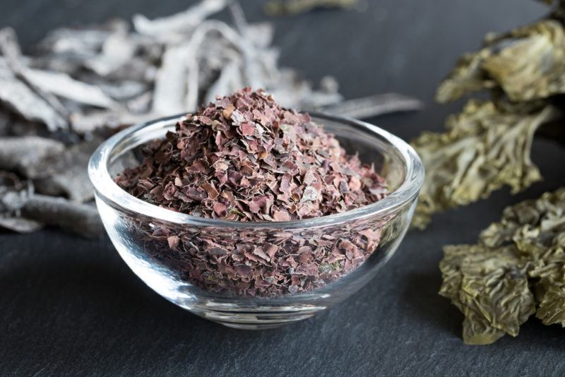 A glass bowl containing dulse with seaweed in the background