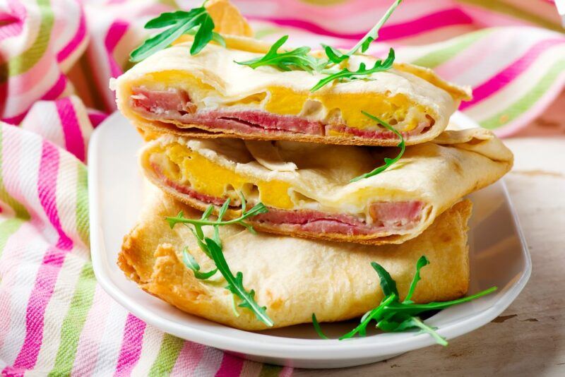 Breakfast pockets made using eggs and bacon in a stack on a white plate