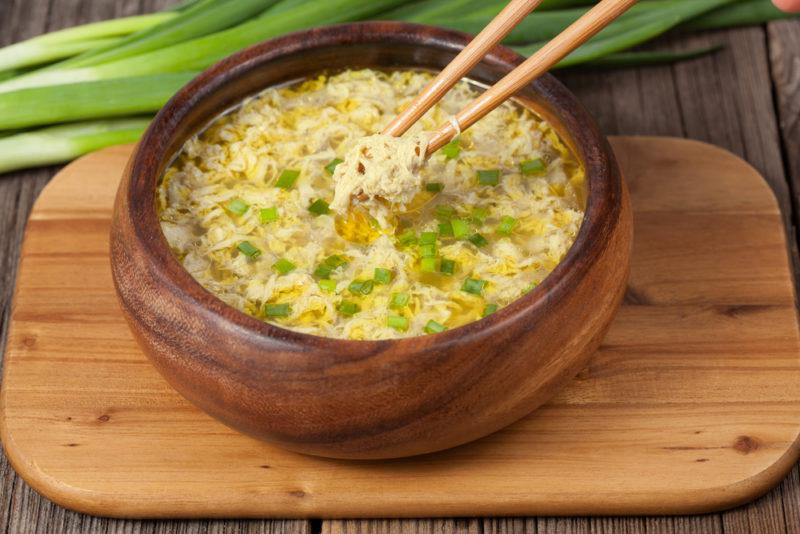 Egg drop soup in a wooden bowl with chopsticks