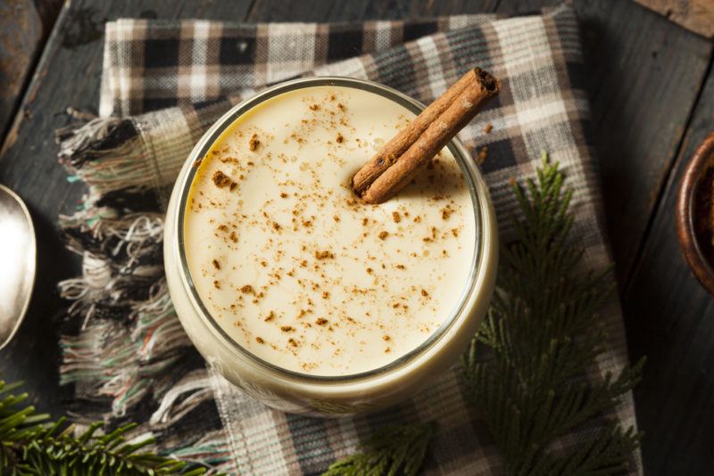 A glass of eggnog with a cinnamon stick