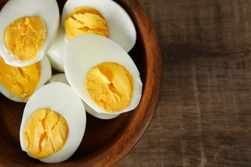 A wooden bowl containing cooked eggs