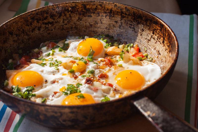 Fried eggs in a pan with ham and parsley