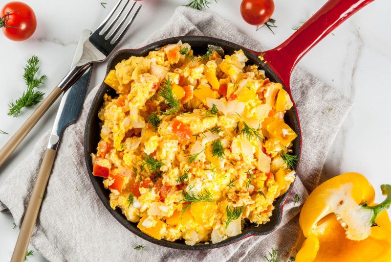 A fry pan with scrambled eggs and veggies