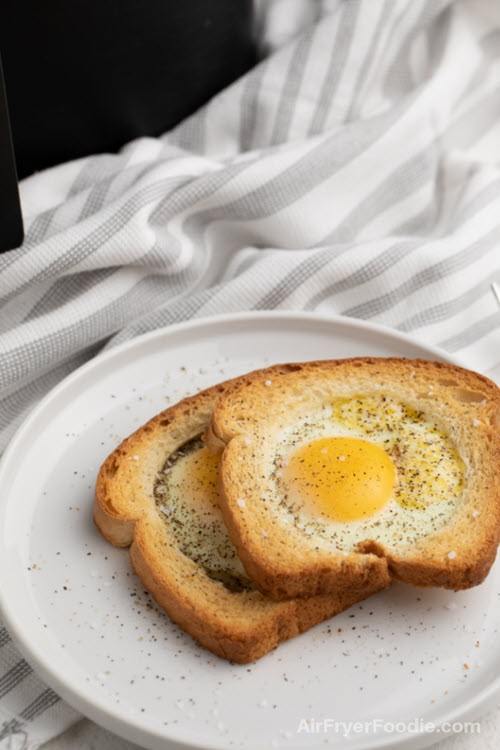 Two pieces of eggs in a basket toast on a white plate