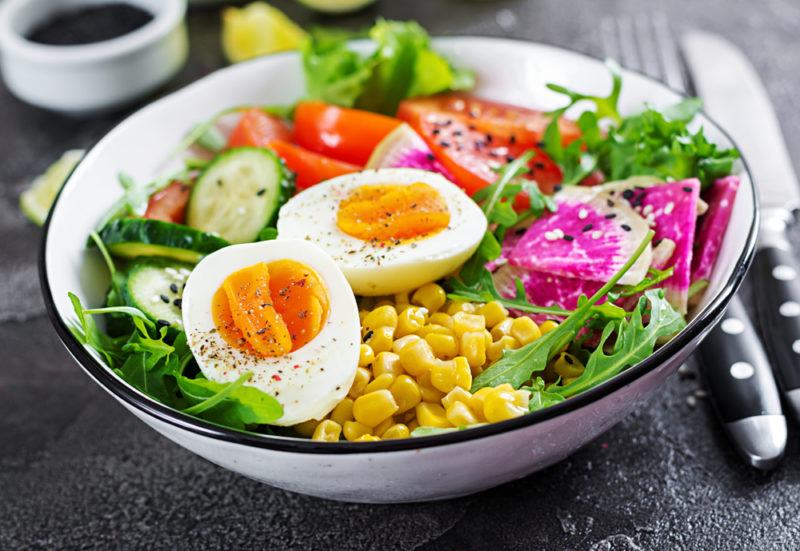 A buddha bowl with eggs, greens, and vibrant colors