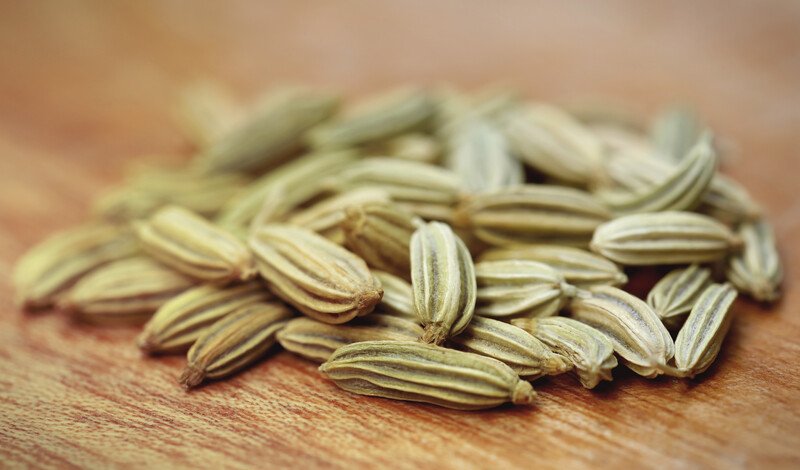 closeup image of fennel seeds on a wooden surface