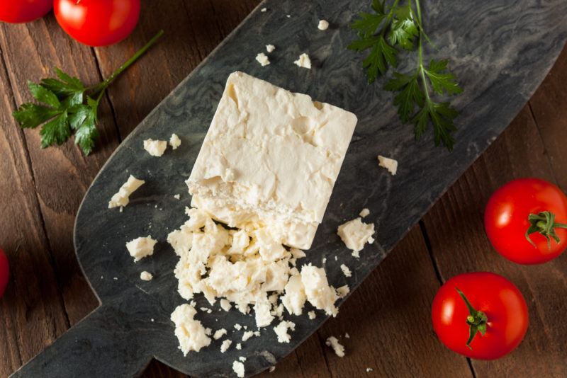 A partially crumbled block of feta on a black board