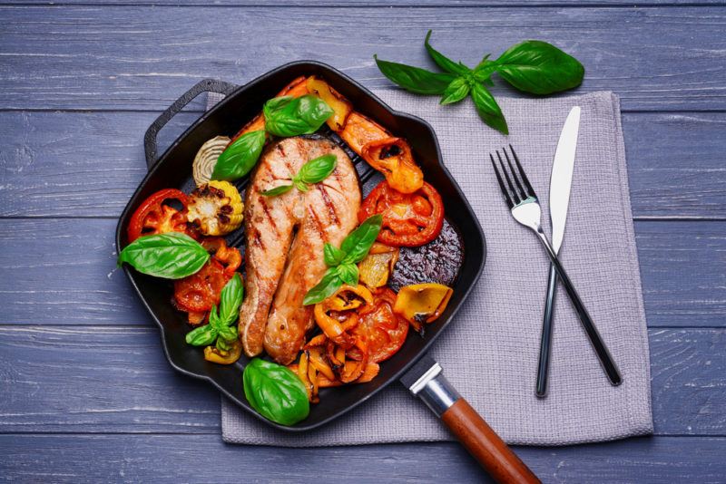 A cart iron pan containing cooked fish and tomatoes