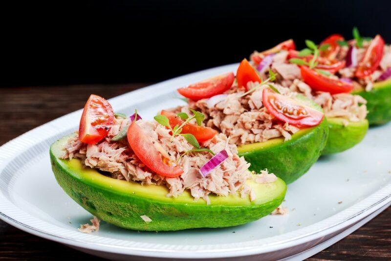 Three avocado halves with fish and tomatoes