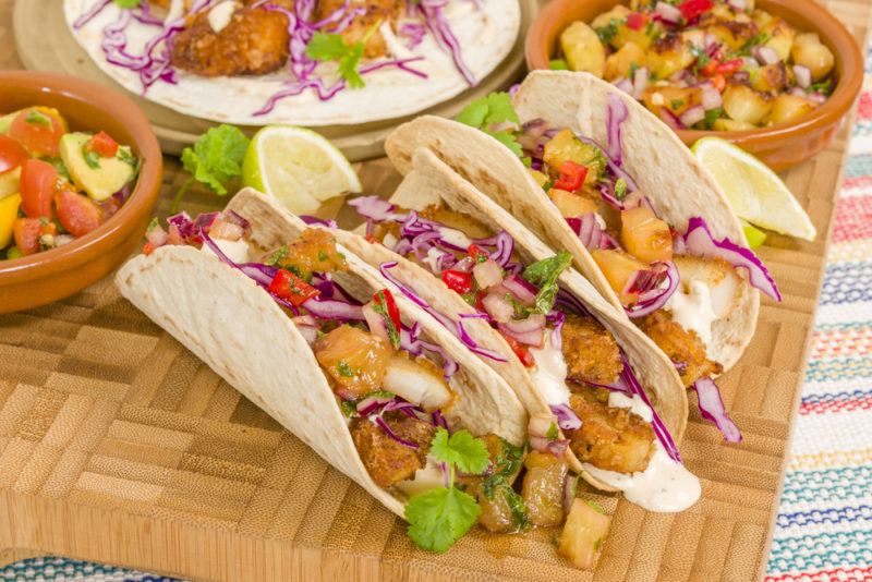 Fish tacos on a wooden board with fillings