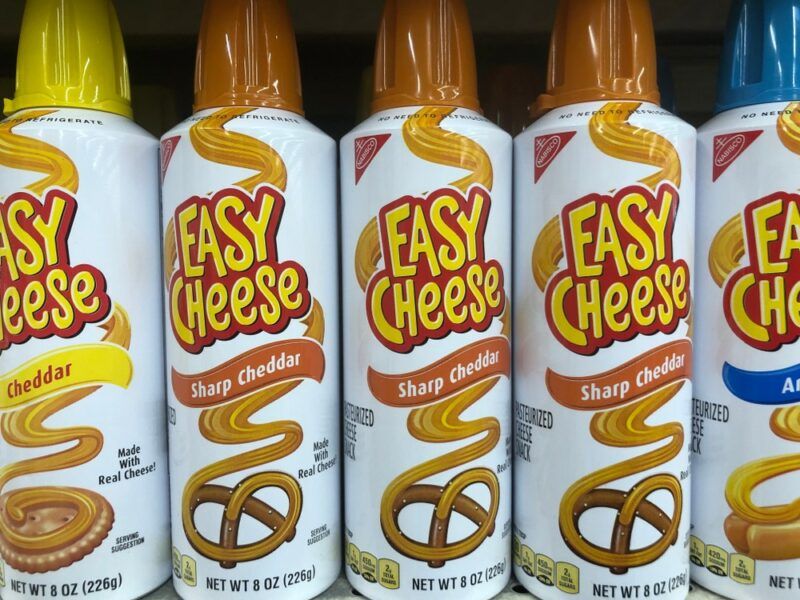 A few cans of Easy Cheese on a grocery store shelf