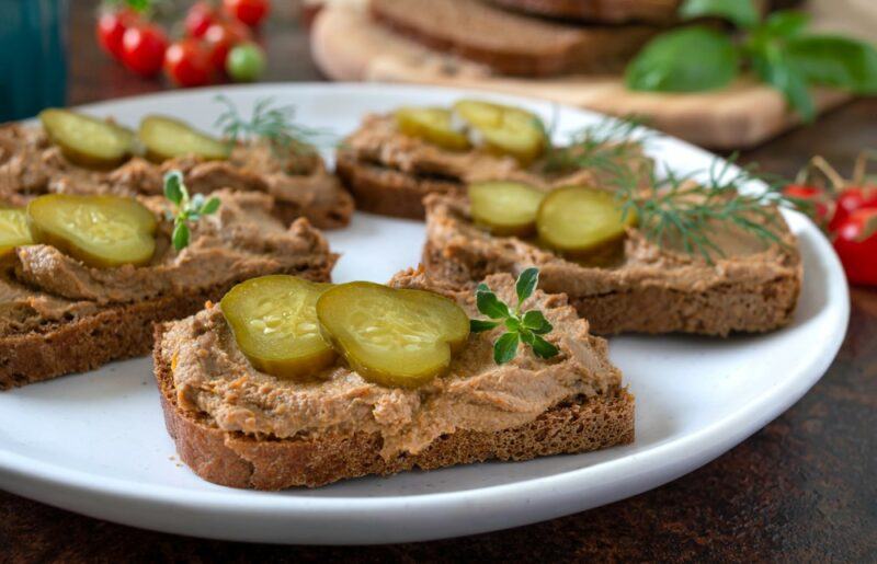 Five pieces of toast with spread and slices of pickles