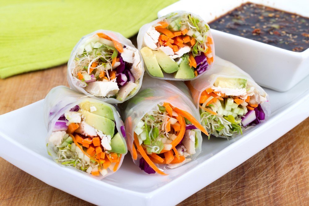 A white dish that includes five wraps made with rice paper and vegetables