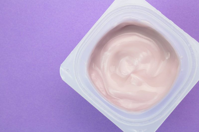 A pottle of pink flavored yogurt against a purple background