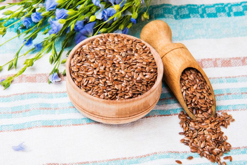 A wooden bowl and scoop of flax seeds