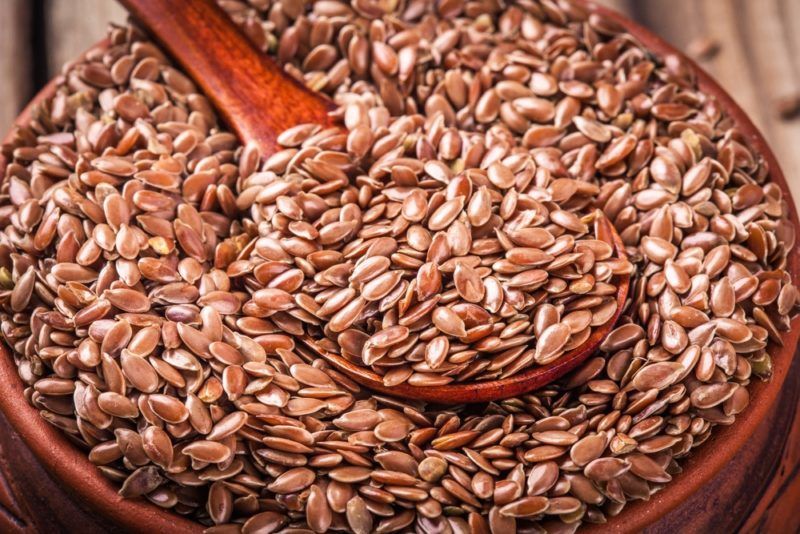 A large bowl of flaxseeds with a spoon