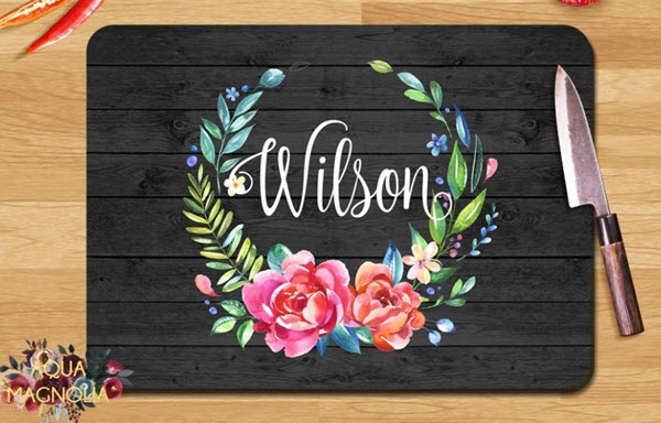 Floral-Wreath-Cutting-Board | Food For Net A black cutting board with a bright floral wreath and white text.