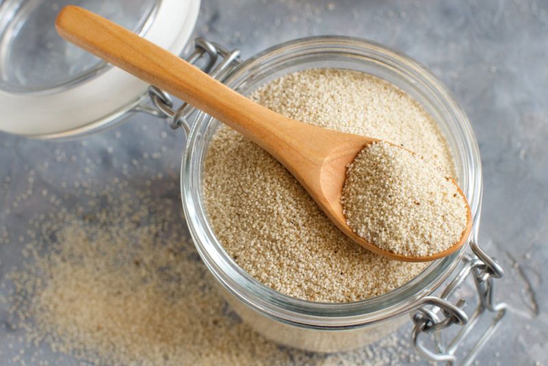 A glass jar containing fonio with a spoon