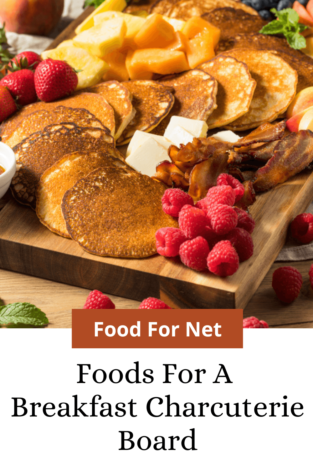 A wooden board containing a variety of breakfast treats, including pancakes and fruit, looking at the best foods for a breakfast charcuterie board