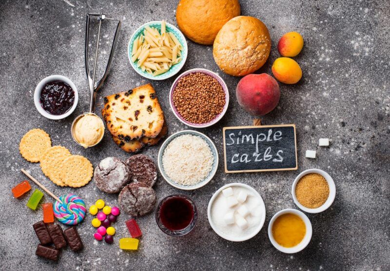 Containers of simple carb foods, including bread and candy, along with a label that says simple carbs