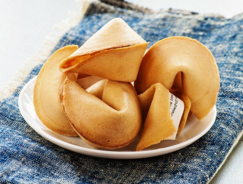 A white plate on a blue tray, containing fortune cookies